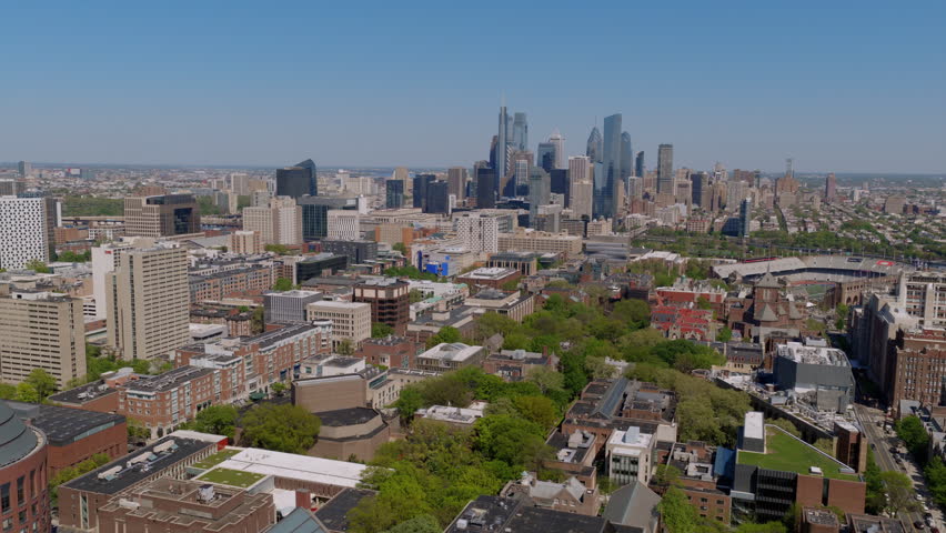 Aerial drone view of the University of Pennsylvania campus with tree-lined walks, brick academic buildings, and Philadelphia