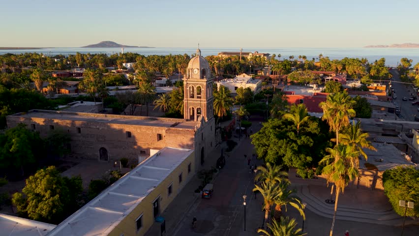 See the sunset at Loreto Mission church in Baja California Sur, Mexico, showcasing the town and desert landscape from above