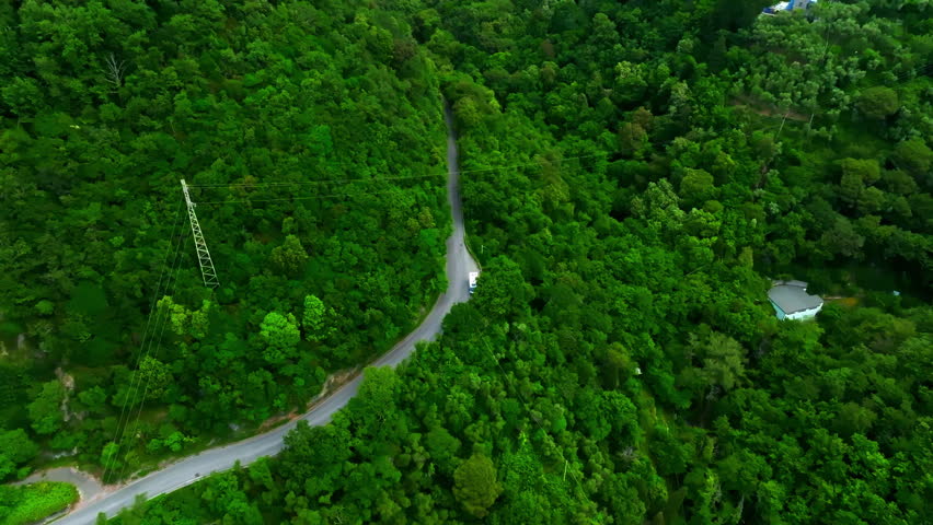 Aerial view of a RV parked on a mountain road in green forests of Liguria, Italy