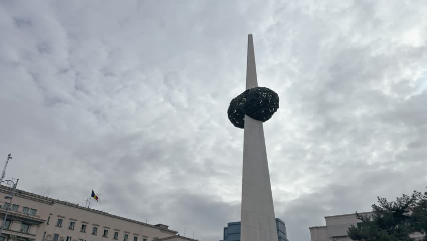 The Memorial of Rebirth in Revolution Square, Bucharest, Romania, stands tall against a cloudy sky. This prominent monument commemorates the victims of the 1989 Romanian Revolution.