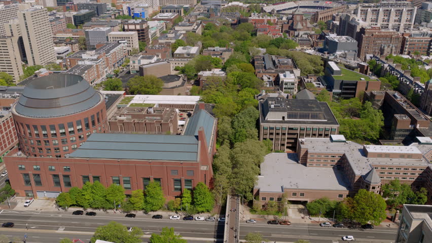 Aerial drone view of the University of Pennsylvania campus showcasing the rounded Palestra-area buildings, tree-lined Locust Walk, and mixed academic architecture.