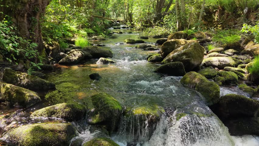 Vaos River Rushing Through Rocks Near Lumeares Bridge In Galicia, Spain. Low Aerial Shot