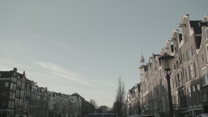 Wide shot of an Amsterdam canal surrounded by historic buildings. The scene showcases the harmony between water and urban architecture, reflecting the iconic landscape of Dutch canals.