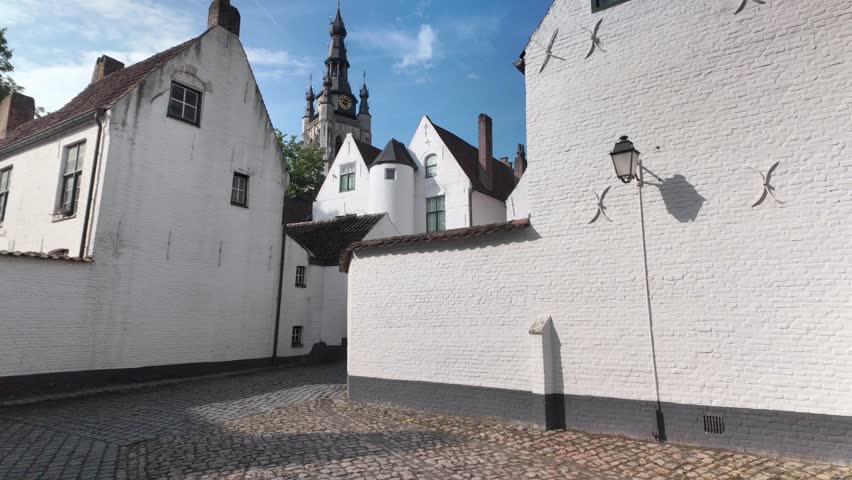 UNESCO beguinage Kortrijk Belgium tiltup view of historic white houses and church tower under blue sky