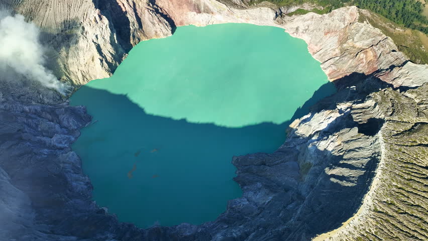 Aerial view of fog at Kawah Ijen volcano with turquoise sulfur water lake at sunrise.Amazing nature landscape view at East Java,Indonesia.Beautiful light Natural landscape background