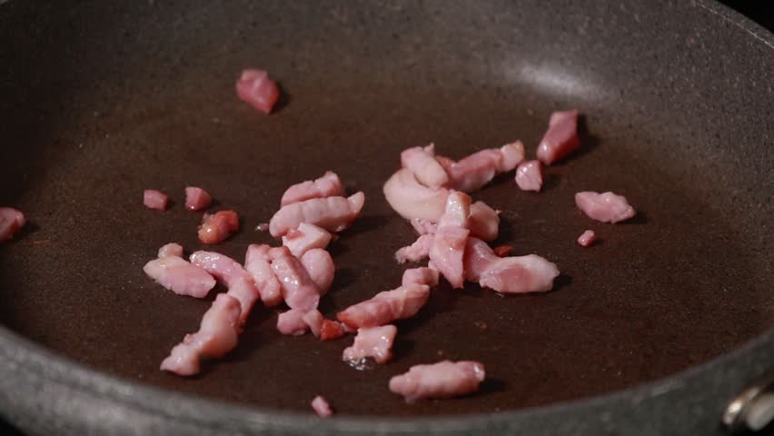 Close-up of fresh green asparagus spears and savory bacon slices sizzling together in a hot frying pan