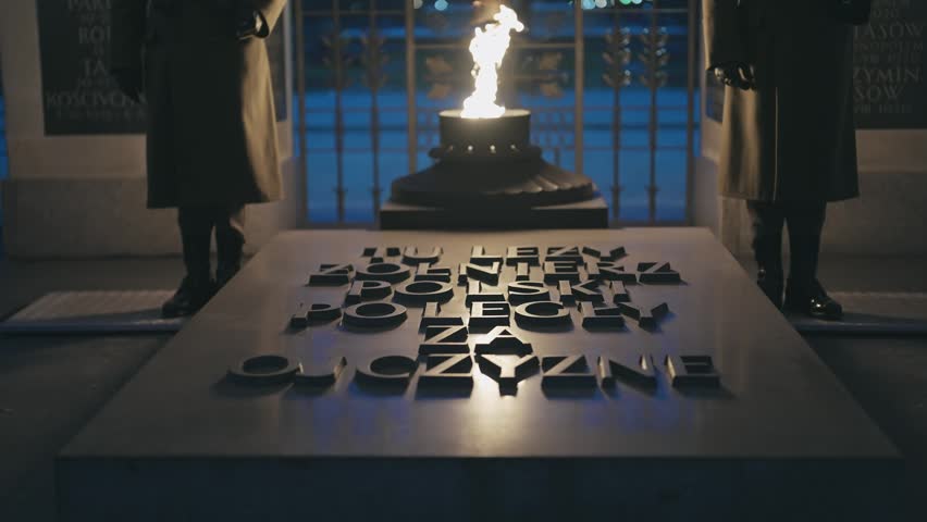 The Tomb of the Unknown Soldier in Warsaw, Poland, at night, with an eternal flame and inscribed memorial. Guards stand vigil, symbolizing profound national remembrance and historical sacrifice.