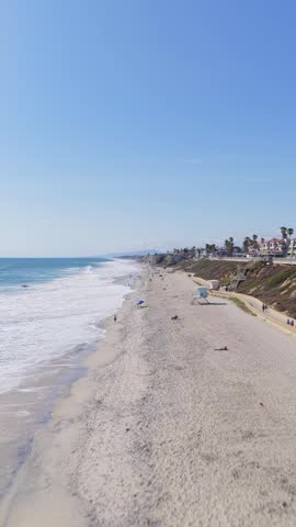 People sunbathing and relaxing on Carlsbad State Beach seashore in California. Flying above sand, ocean waves, coastal landscape on sunny american summer day