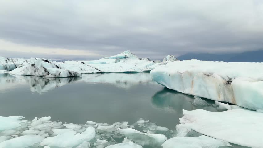 Drone footage of Jökulsárlón in Iceland, capturing floating icebergs drifting across the glacier lagoon and showcasing the raw beauty of the Arctic landscape.
