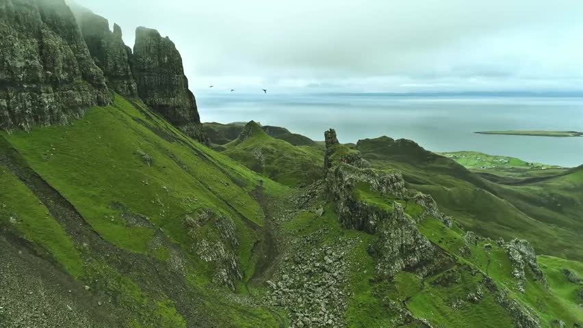 Cinematic drone footage slowly gliding along a beautiful Scottish shoreline, revealing rugged coastal landscapes, peaceful waters, and dramatic natural scenery. The smooth aerial movement captures the