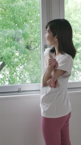 Back view of woman stretching by window