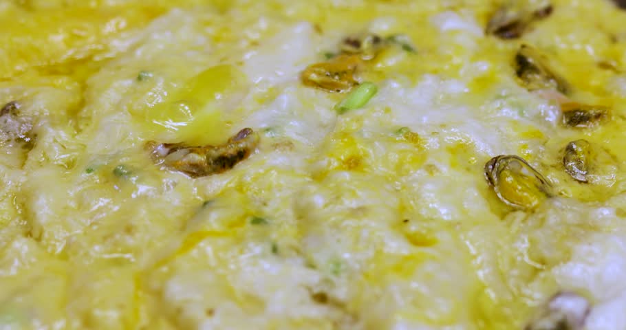 Oyster omelet cooking on a hot pan with metal spatulas. Delicious street food, live cooking, and tasty seafood meal preparation, close-up