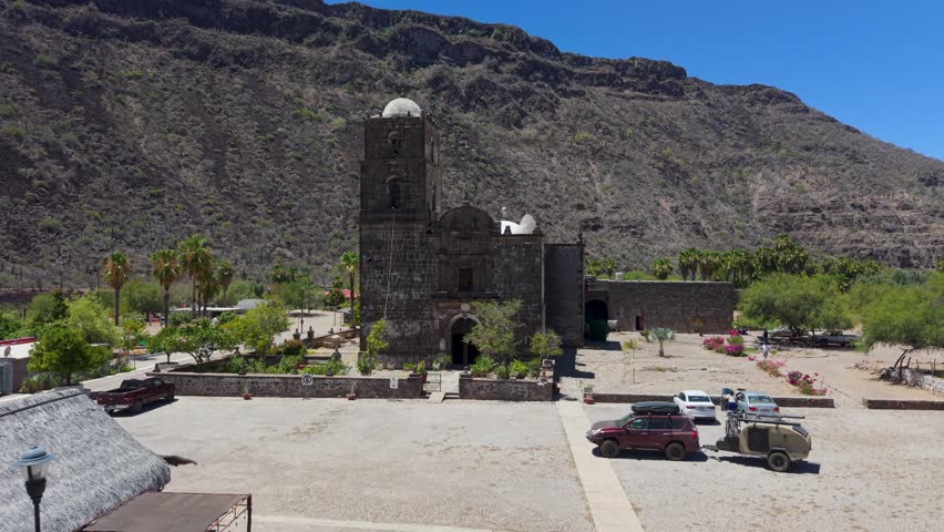An SUV with a teardrop camper trailer visits the San Javier historic mission in Baja California Sur near Loreto.