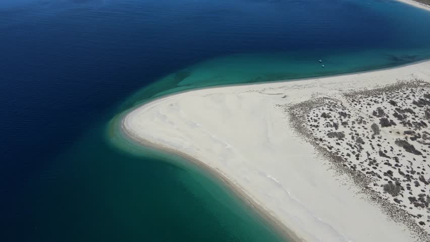 Aerial drone footage of the pristine coastline of Isla Cerralvo (Jacques Cousteau Island) in the Gulf of California, Baja California Sur, Mexico. Crystal-clear turquoise waters, white sand beaches and dramatic desert landscape create a stunning natural seascape in the Sea of Cortez.