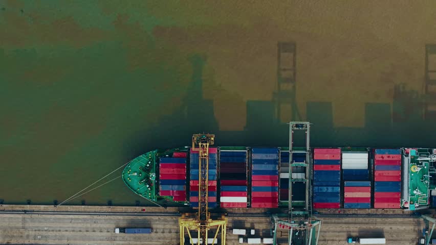 Aerial view of container ship unloading at industrial port quay.