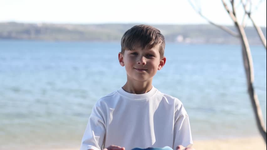 Young boy putting on a protective helmet before a bike ride near the waterfront. Child safety, active lifestyle and outdoor recreation concept.