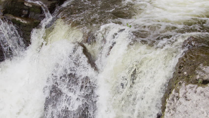 A powerful waterfall crashes over rugged rocks, creating foamy white water in Norway. Ideal for travel content or adventure documentaries.