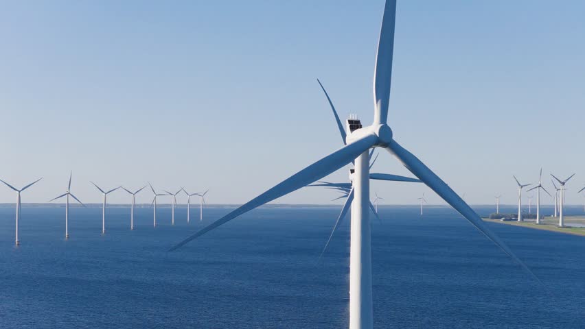 Aerial drone footage of offshore wind turbines in the open sea. Sustainable marine energy farm generating clean power. Industrial and technological video.