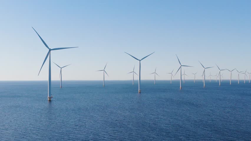 Aerial drone footage of offshore wind turbines in the open sea. Sustainable marine energy farm generating clean power. Industrial and technological video.