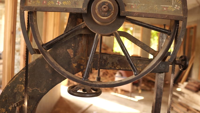 Close up of a rusty vintage industrial bandsaw wheel inside a carpentry workshop.