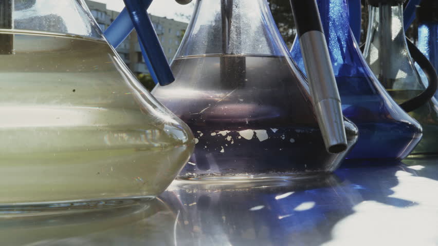 Close-up, hookahs filled with water stand on a counter in the park, glowing with the setting sun