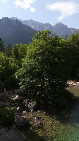 Vertical aerial of a wooden boathouse on the emerald Obersee below steep mountains, Berchtesgaden National Park, Bavaria, Germany