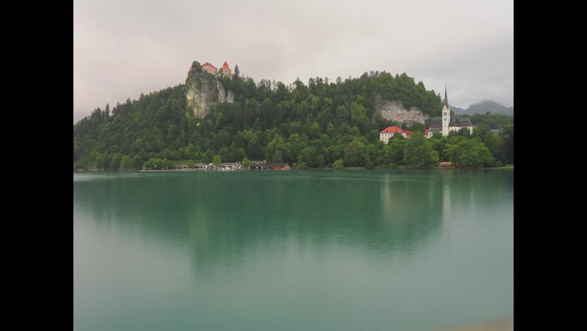 4K Timelapse captured around blue hour in Bled lake, Slovenia. Castle and church in view reflected in lake water.