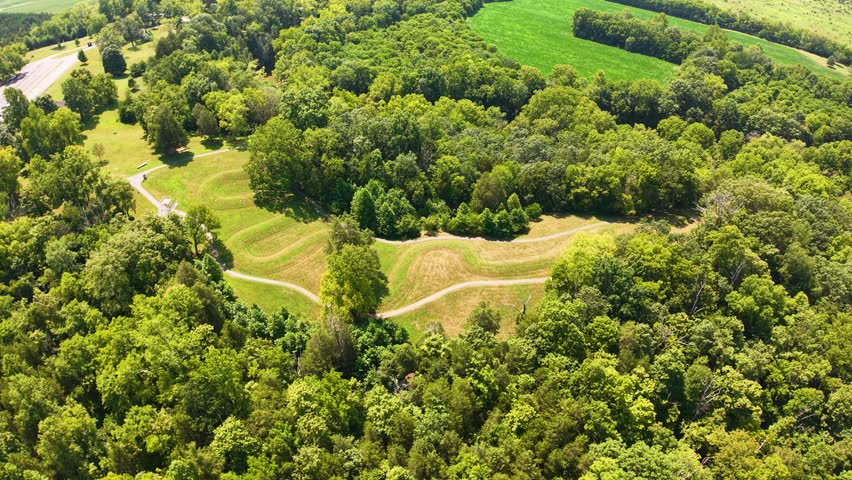 Aerial view of an ancient effigy mound in a forested area with walking paths.
