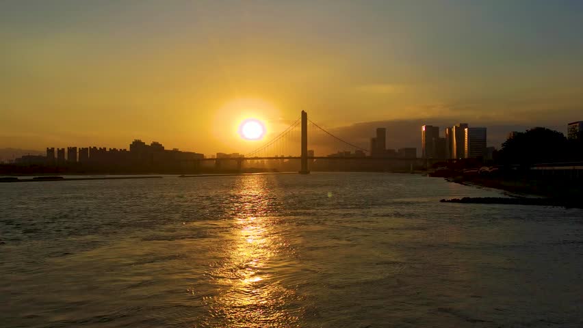 Stunning sunset over a modern city skyline with a large suspension bridge
