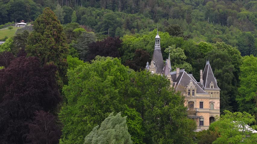 Majestic fairytale castle Hunegg with spires and turrets emerging from a dense green forest IN Switzerland.