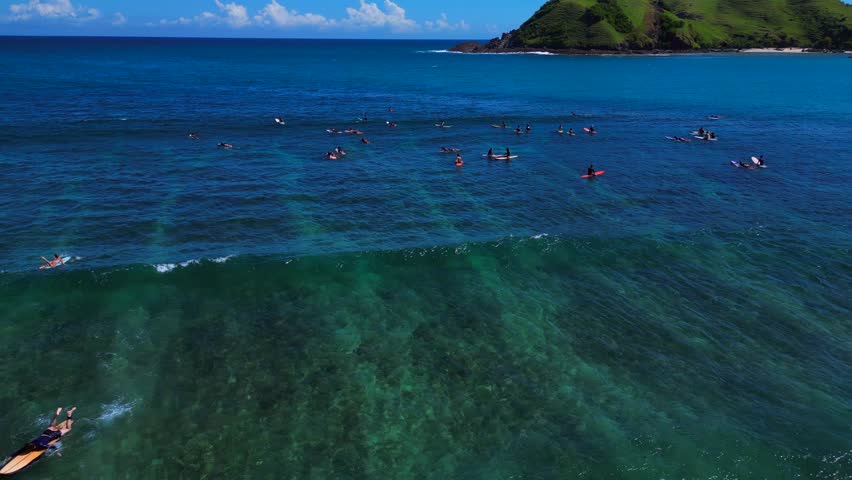 Surfer riding a blue ocean wave on a sunny day. Smooth aerial view drone