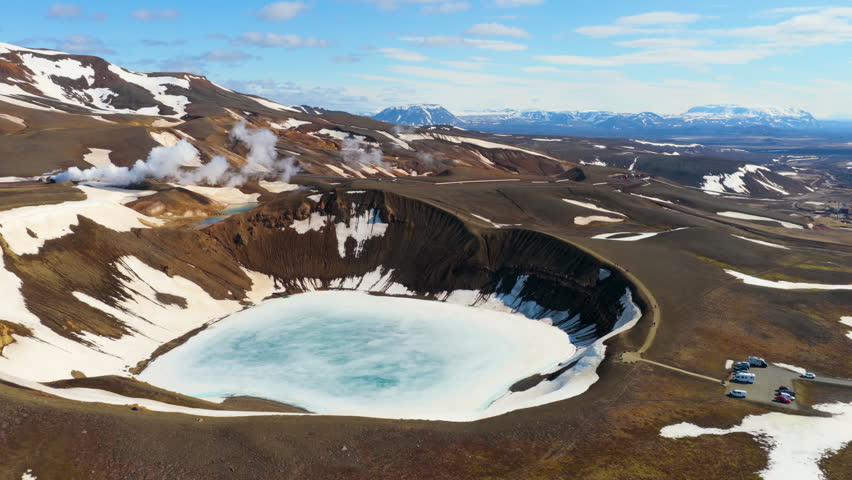 Aerial view of a volcanic crater lake Krafla with a frozen basin, steam rising from the slopes. Iceland