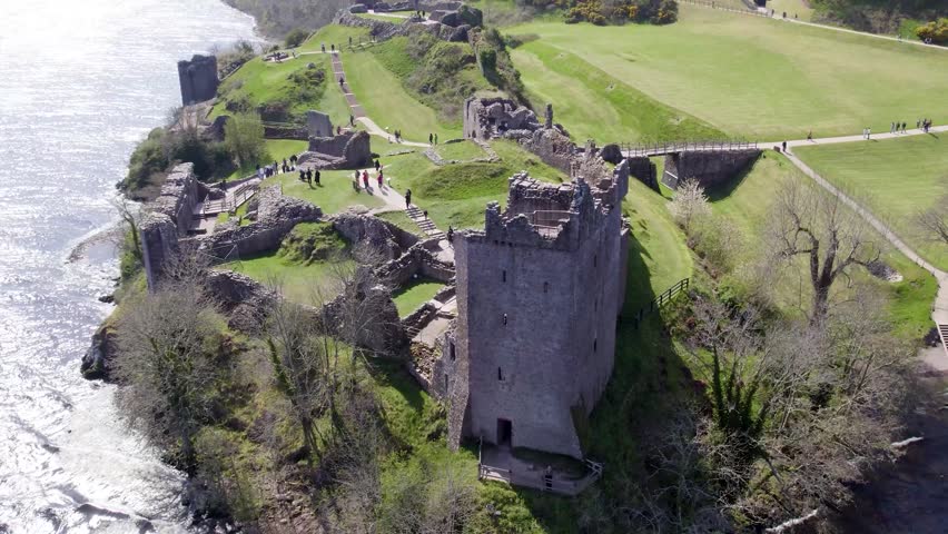 A crane drone shot revealing the ruins of a castle near Loch Ness.