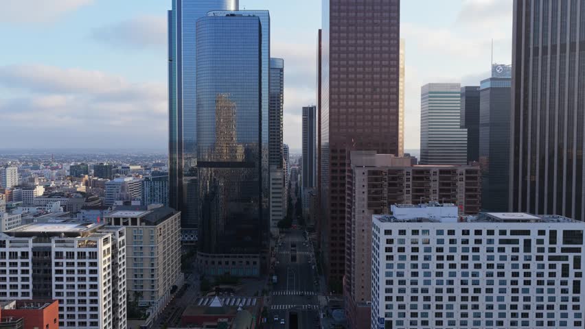 Financial district of Los Angeles from an elevated position with reflections of a tower on glass skyscraper, showcasing modern business buildings and urban landscape