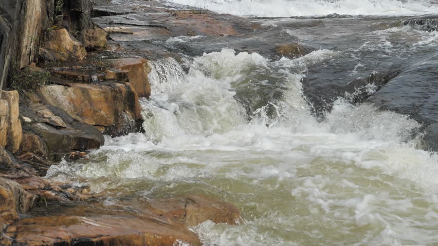 The waterfall has a rapid flow and splashes of water.