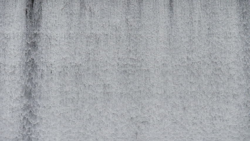 The waterfall has a rapid flow and splashes of water.