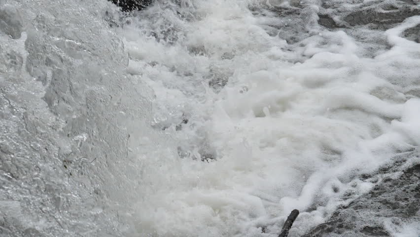 The waterfall has a rapid flow and splashes of water.