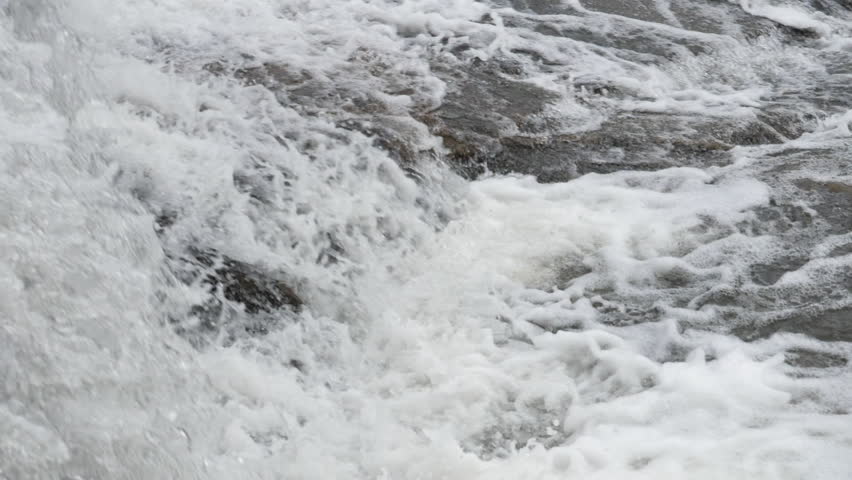 The waterfall has a rapid flow and splashes of water.