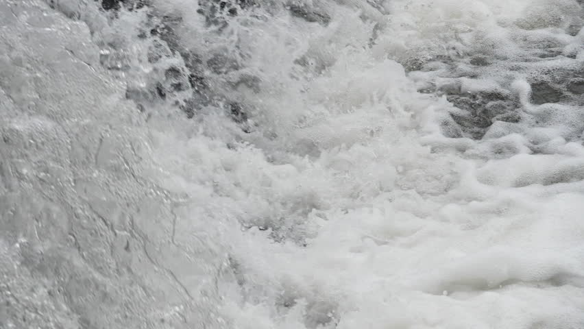The waterfall has a rapid flow and splashes of water.