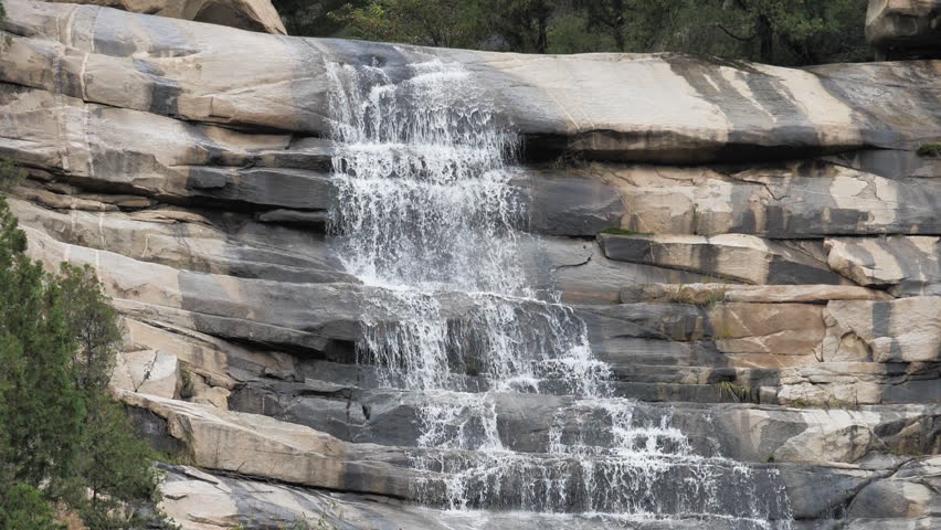 The waterfall has a rapid flow and splashes of water.