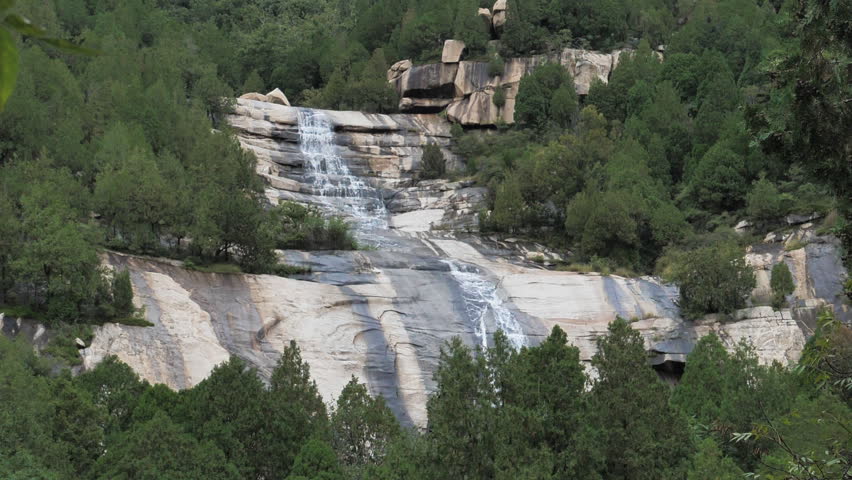 The waterfall has a rapid flow and splashes of water.