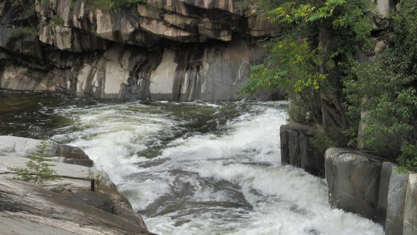 The waterfall has a rapid flow and splashes of water.
