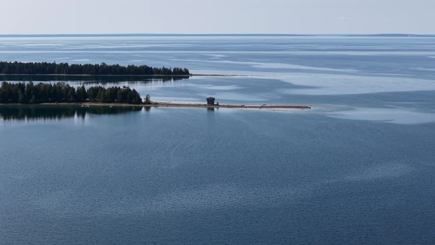 Drone aerial shot of a remote lake shore with a small building in Hessel, Michigan, overlooking Lake Huron.
