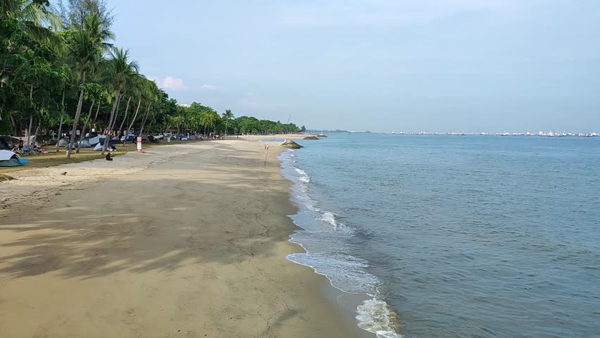 Long Stretching Sandy Beach Shoreline Calm Sea at East Coast Park Singapore Beach with Visitors Camping Palm Trees Coastal Recreation Urban Park