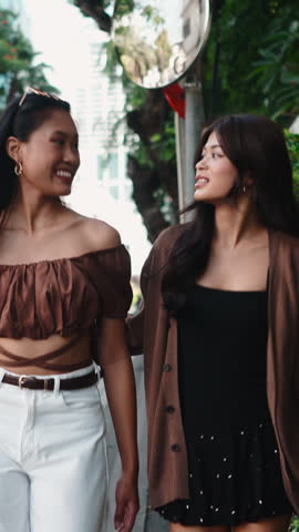 Two cheerful thai friends enjoying a walk and talk in the city