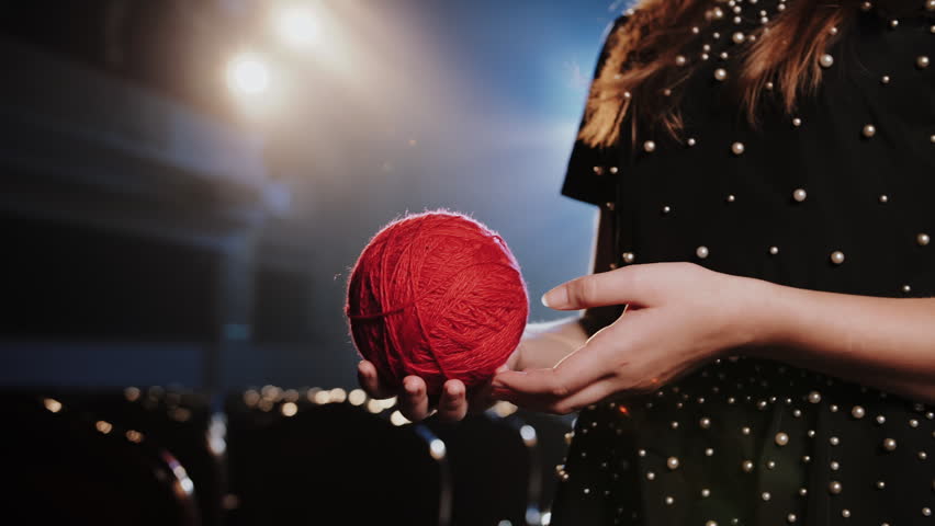 Fashion Designer with Red Yarn Ball Under Glowing Stage Lights