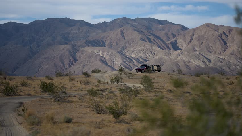 Watch a teardrop camper trailer and SUV set up for camping on the Thimble Trail in Anza Borego State Park under the desert sky.