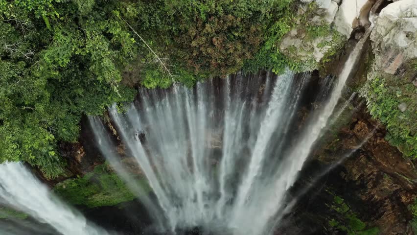 A waterfall cascades down rocky terrain into a pool below shown as a time-lapse sequence with blurred water movement. The