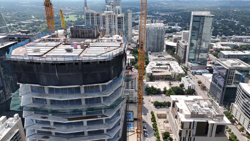 Circular pan and tilt of camera drone gimbal while flying around glass skyscraper under construction in downtown Austin Texas.