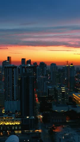 Dynamic drone movement over downtown Miami during golden hour. Cinematic view of skyscraper architecture against colorful evening sky. Urban landscape with glowing street lights and high rise.